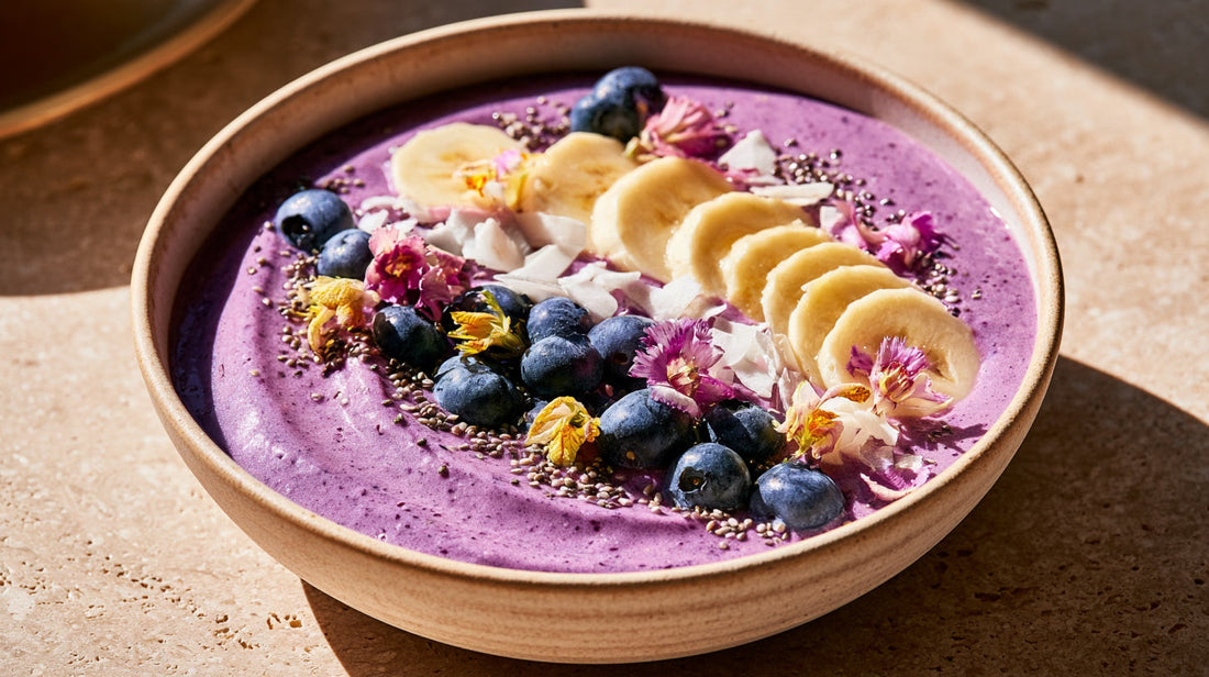 Smoothie bowl à l'ube garni de bananes, myrtilles, noix de coco et graines de chia.